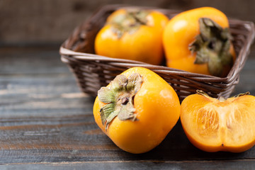 Fresh persimmon fruit in a basket on wooden table