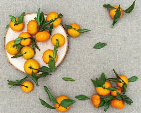 Tangerines (oranges, clementines) with green leaves on sackcloth background. Top view.