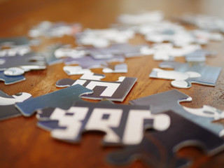 Jumbled blue and white jigsaw puzzle pieces on wooden table