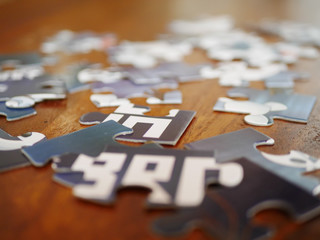 Jumbled blue and white jigsaw puzzle pieces on wooden table 