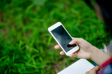 Girl playing phone on hand for online communication and contact Wear red shirt and green background And there is a copy space.