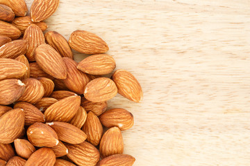 heap almonds top view frame or border on wooden background.