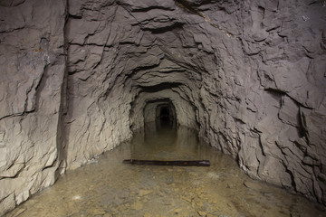 Underground abandoned gold iron ore mine shaft tunnel gallery passage with water flooded
