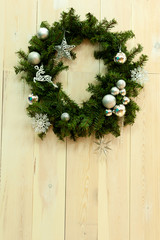 Christmas wreath on a light wooden wall. With free space
