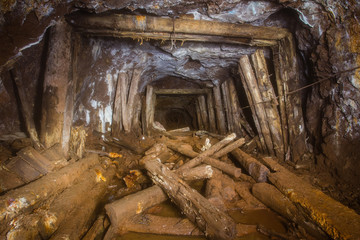 Underground abandoned gold iron ore mine shaft tunnel gallery passage with wood timbering