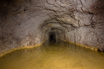 Underground abandoned gold iron ore mine shaft tunnel gallery passage with water flooded