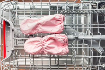 Pair of baby mittens lies in the dishwasher for washing