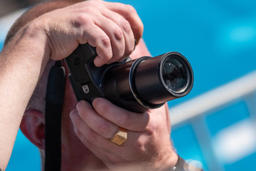 A man photographs holding a camera with both hands.