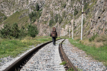 The traveler walks along the mountain along the railway.