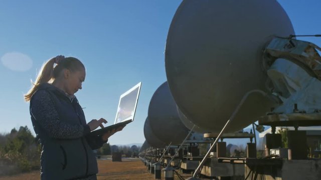 Woman student operator of institute of Solar Terrestrial Physics monitors communication equipment in notebook. Unique array solar radio telescope. Sun Solar Radio Telescope. The 'Quasar' observatory