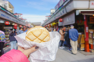 Asakusa,Tokyo - October 31 2018 : Woman hand holding melon pan at Nakamise Shopping Street Asakusa temple. Landmark in Japan. Japanese Language.