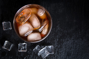 Whiskey with ice on black stone table. Top view with copy space