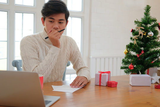 man thinking what to write on christmas letter greeting card holiday wishes with xmas decoration