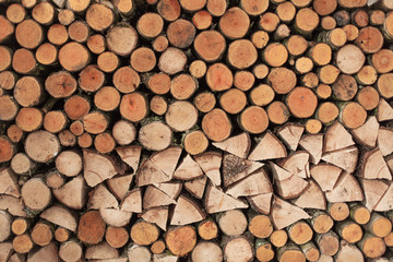 A woodpile of round logs and wood chucks in the countryside.