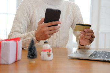 man holding credit card & smart phone for online shopping.  male buyer buying christmas gift on internet. xmas new year holiday celebration