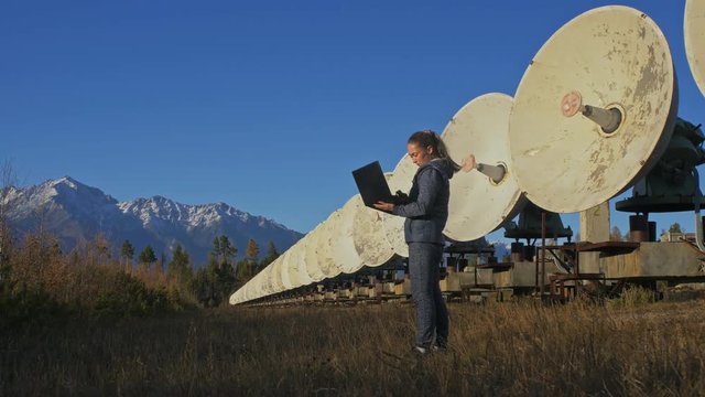 Woman student operator of institute of Solar Terrestrial Physics monitors communication equipment in notebook. Unique array solar radio telescope. Sun Solar Radio Telescope. The 'Quasar' observatory