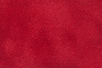 Dark red matte background of suede fabric, closeup.