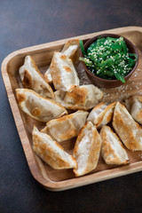 Close-up of fried japanese gyoza and chuka salad on a wooden serving tray, vertical shot