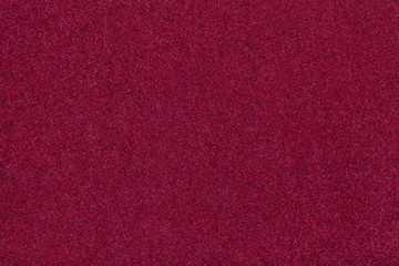 Dark red matt suede fabric closeup. Velvet texture of felt.