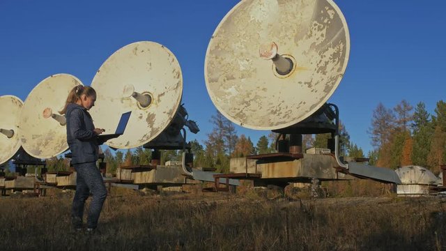 Woman student operator of institute of Solar Terrestrial Physics monitors communication equipment in notebook. Unique array solar radio telescope. Sun Solar Radio Telescope. The 'Quasar' observatory