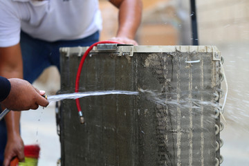 Worker to cleaning coil cooler of air conditioner by water for clean a dust on the wall in customer...