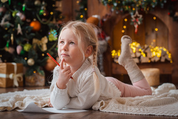 Merry Christmas and Happy Holidays. little child girl writes letter Santa Claus and dreams of a...