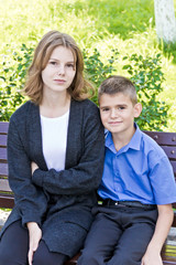 Fototapeta premium Brother and sister are sitting on bench