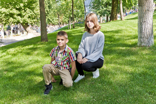 Brother and sister are sitting on green grass