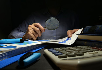 Auditor checks financial report with magnifying glass. Internal audit and business analysis.