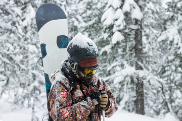 Portrait bearded man ski goggles holding snowboard in the mountains