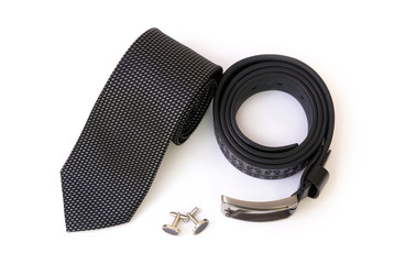Rolled black men's tie and a leather belt with a couple of cuff links isolated on white background,...