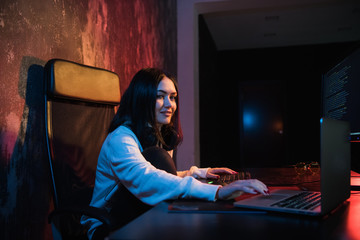 Young woman sit in front of personal computer and laptop, php Programming Html Coding Cyberspace Concept. Looking at camera