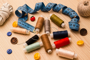 Fototapeta na wymiar Blue measuring tape, buttons and multicolored thread spools