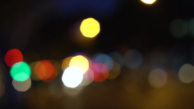 Defocused or soft focus lights of cars, scooters, motorbikes and traffic driving on city streets at night