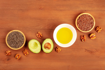 Fototapeta na wymiar Healthy omega 3 vegan diet food products. Avocado, walnuts, chia seeds, flaxseeds, shot from above on a dark rustic wooden background with copy space