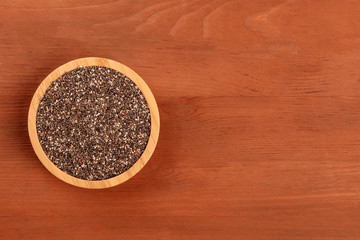 A photo of chia seeds, shot from above on a dark rustic wooden background with copy space