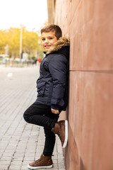 Little boy leaning on a wall. Urban scene.