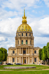 View on the Hotel des Invalides and its golden dome, under which rests the tomb of Napoleon Bonaparte, in Paris France, on a summer day under a blue sky white white clouds, seen from the Place Vauban