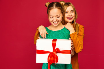 Christmas, x-mas, concept.Two smiling beautiful women in stylish clothes.Girls posing on red...