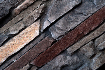 Stone wall of natural stones in different sizes and different colors. Rustic stone veneer in shades of brown color. Wall covering with natural stones