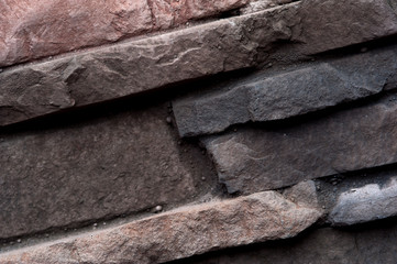 Grey rustic stone in stone wall of natural stones in different sizes and different colors. Rustic stone veneer in shades of brown color