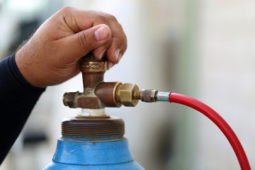 Closeup man's hand operating valve of gas cylinder for welding