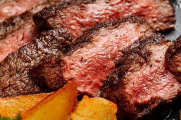 Beef rump steak from marble beef medium rare with potatoes and sauce on stone plate, close-up. Selective focus.