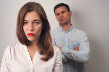 Upset caucasian man crossed folding arms looking at the nape of woman in blue shirt and woman in white blouse having difficulties and problems in relationships. Shoot on white background
