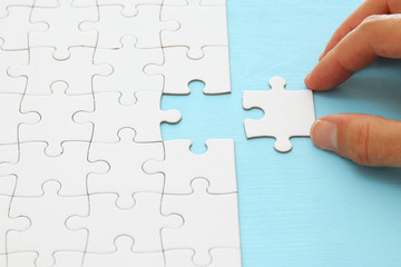 male hand putting the last piece in the puzzle.