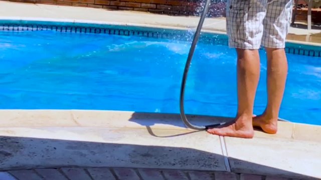 Cleaning - Hosing down a blue solar swimming pool cover 