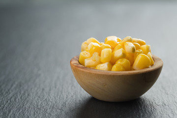 canned corn kernels in woob bowl on slate background
