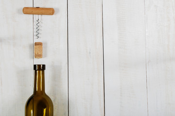 Bottle of wine cork and a corkscrew on a white wooden table.