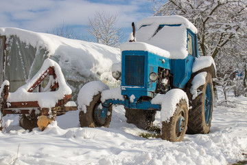 tractor in the snow on the farm,The old tractor is in the snow covered in a farm