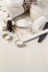 Hand and nail care products. Sea salt. nourishing cream, a variety of nail files, essential oil and a terry towel on a light wooden background.